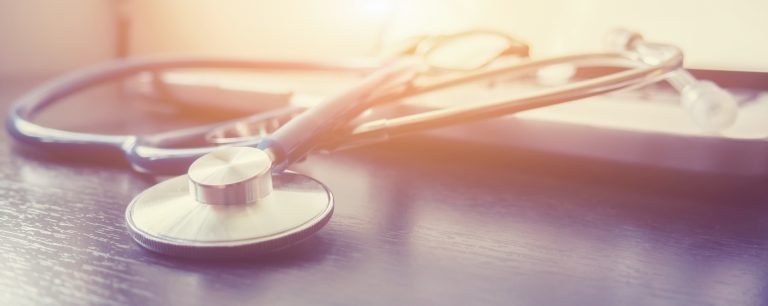 Stethoscope and laptop keyboard on desktop in hospital