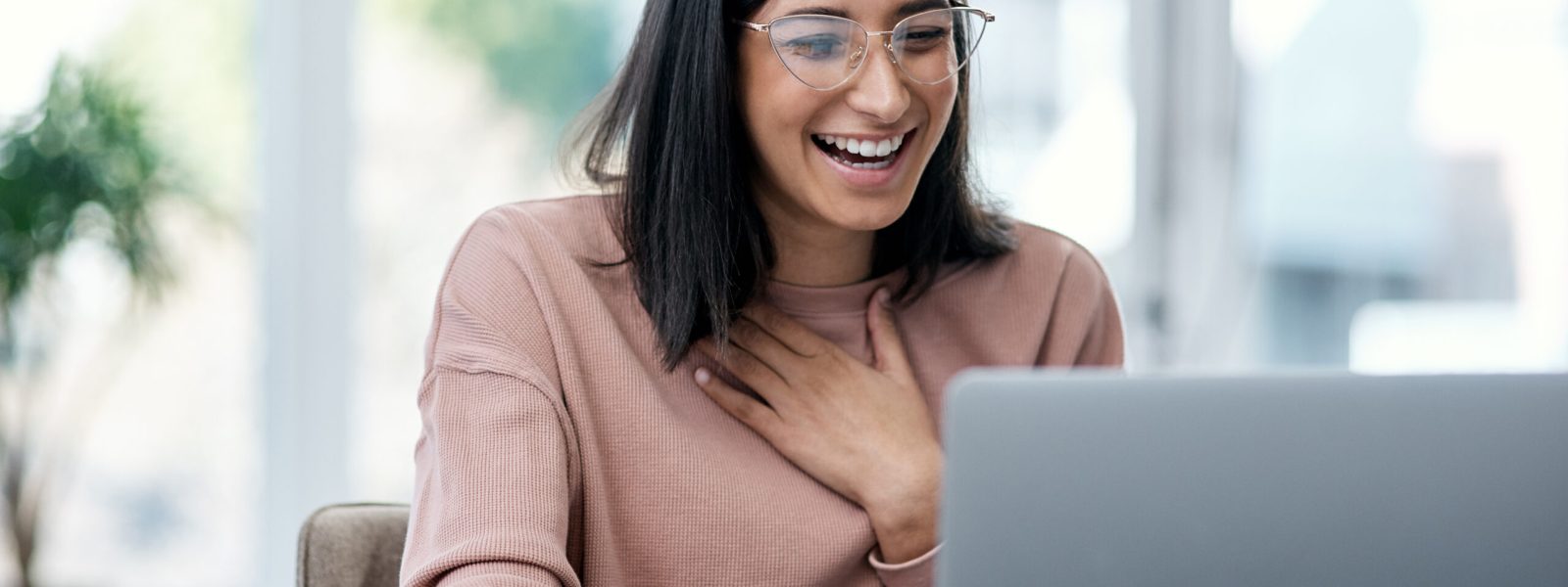 Shot of a young woman using a laptop and looking surprised while working from home.