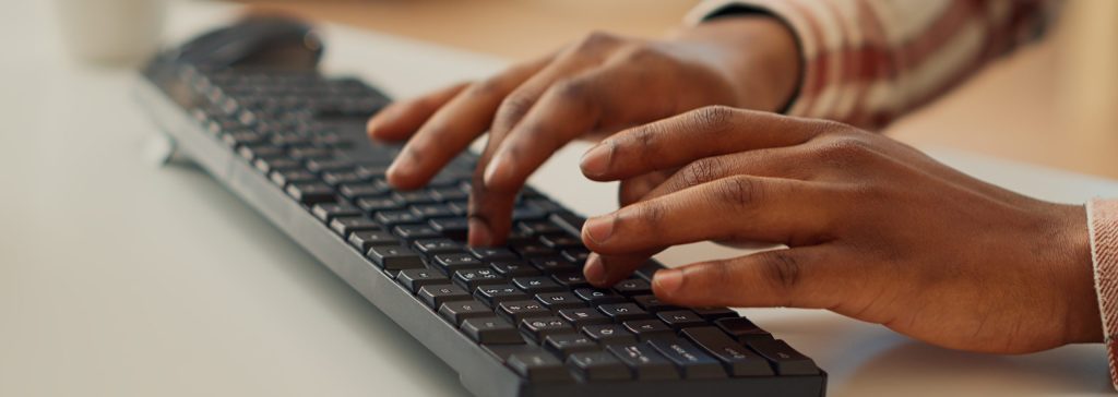 Young adult typing data to create report on computer
